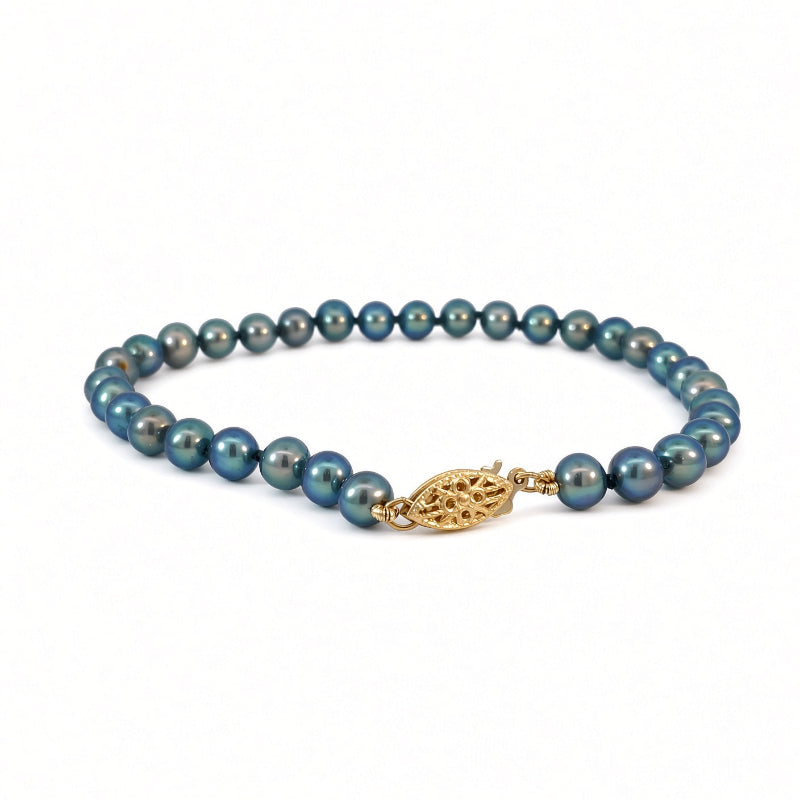 A beaded necklace featuring dark teal-blue pearls with a textured gold leaf-shaped clasp