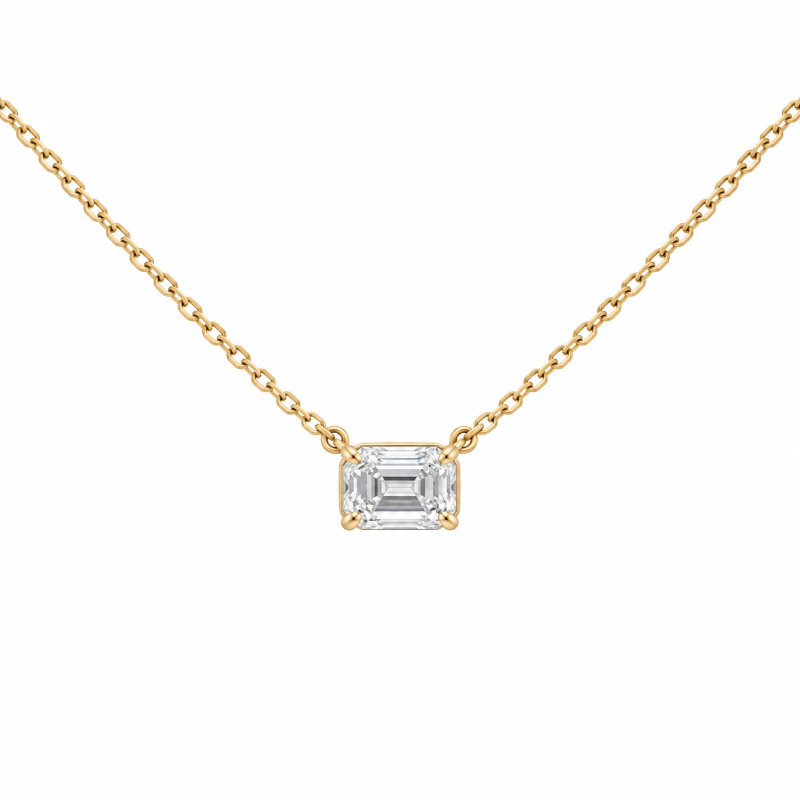 A delicate yellow gold chain necklace featuring an emerald-cut clear gemstone pendant in a four-prong setting,