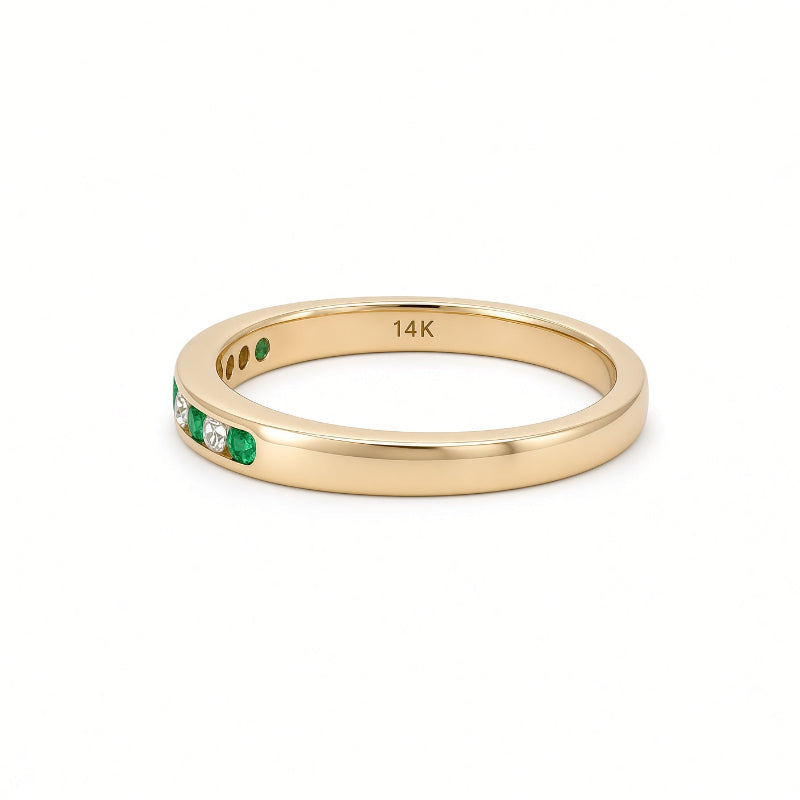 A 14K yellow gold eternity ring featuring a channel-set row of green emeralds and clear round diamonds 