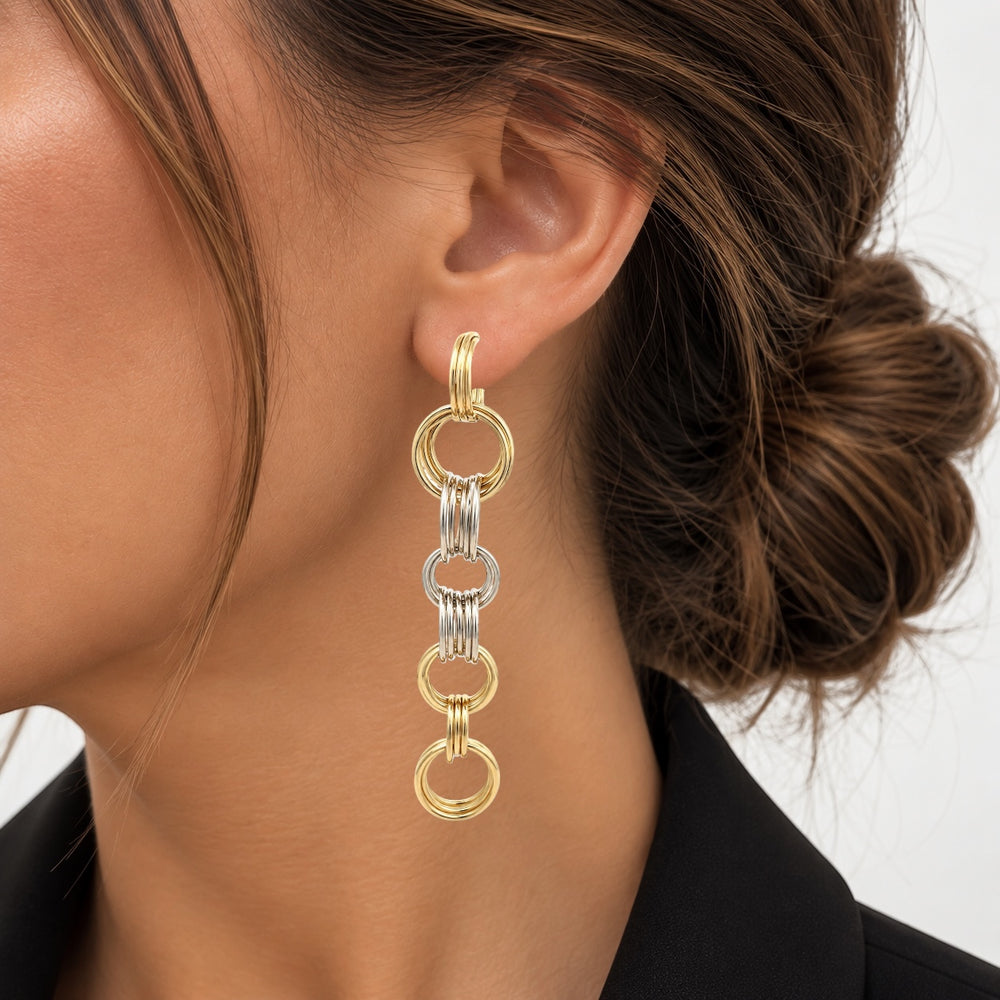 A long dangling earring made of interlocking 18K yellow gold and white rings.