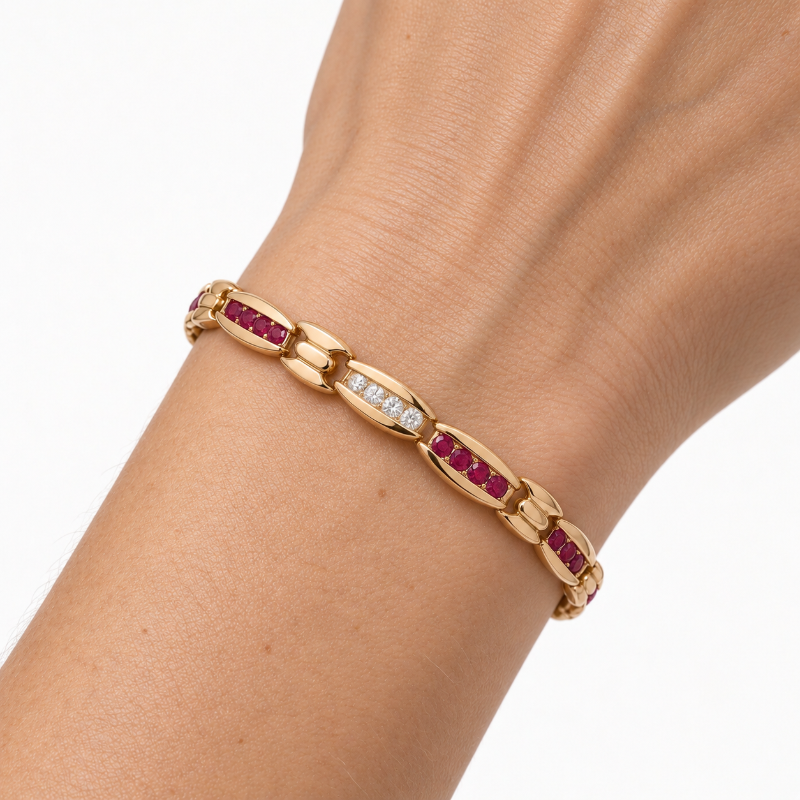 A gold link bracelet with rows of red and clear stones, shown worn on a person&