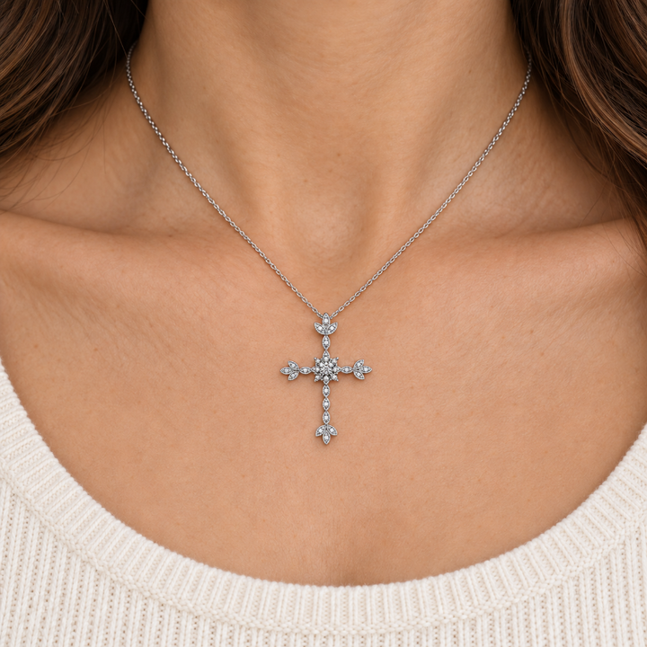 A silver cross pendant necklace with small clear stones